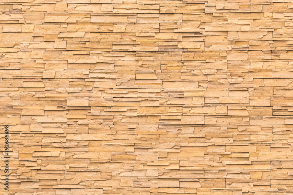 Rock stone brick tile wall aged texture detailed pattern background in dark yellow cream brown color Rock stone brick tile wall aged texture detailed pattern background in dark yellow cream brown color