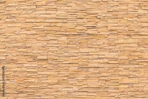 Rock stone brick tile wall aged texture detailed pattern background in dark yellow cream brown color