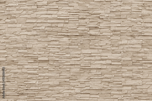 Rock stone brick tile wall aged texture detailed pattern background in light sepia cream brown color