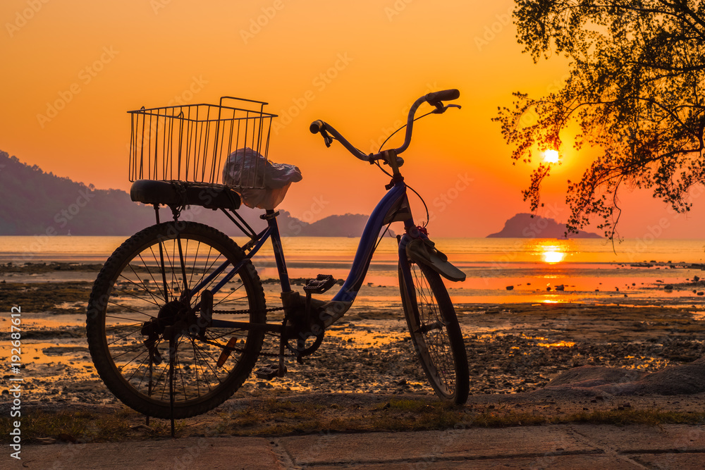 The silhouette of a bicycle on the beach with beautiful sunset