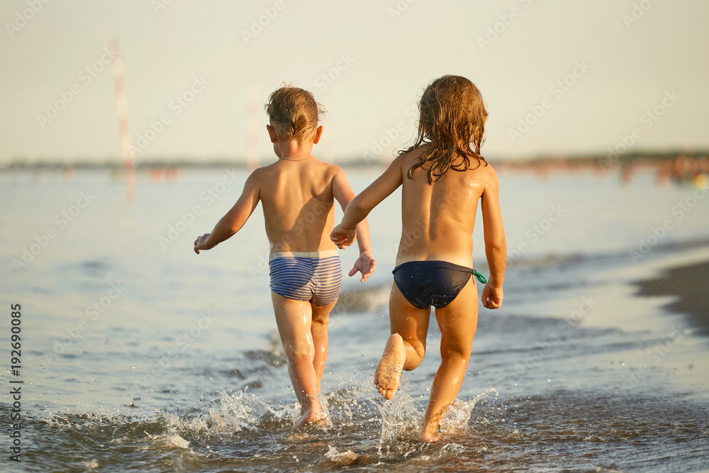 Girl and boy are running along the sea shore Girl and boy are running along the sea shore