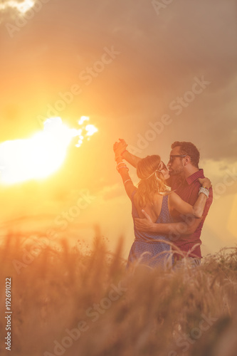 Couple dancing in a wheat field under the sunlight.
