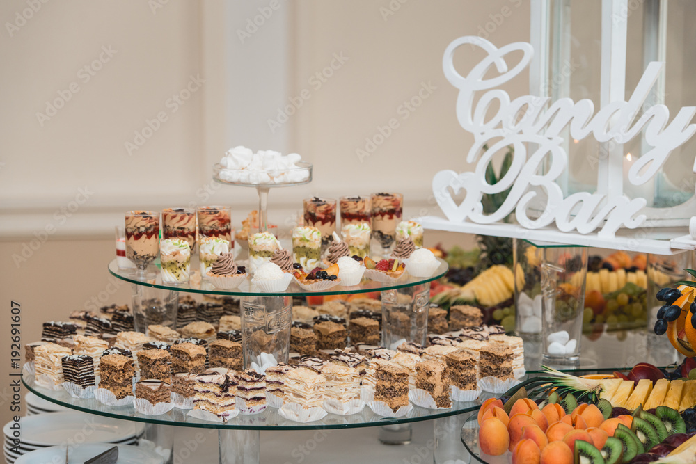 Candybar in a restaurant. Decorated white table fool of sweet pastry