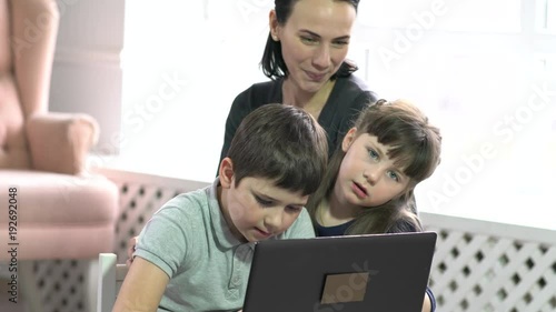 Mom and kids having fun on laptop at home.