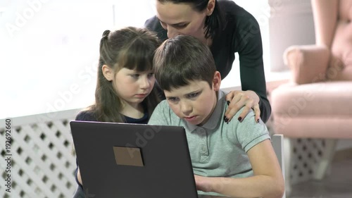 Mom and kids having fun on laptop at home.