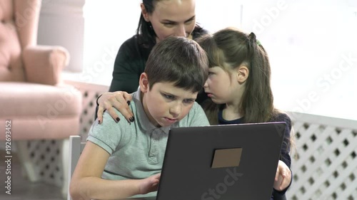 Mom and kids having fun on laptop at home.