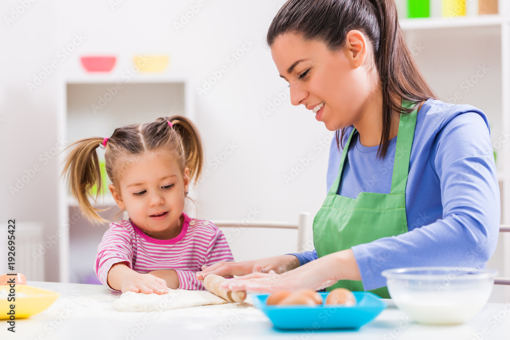 Happy mother and daughter are making cookies in their kitchen. Happy mother and daughter are making cookies in their kitchen.