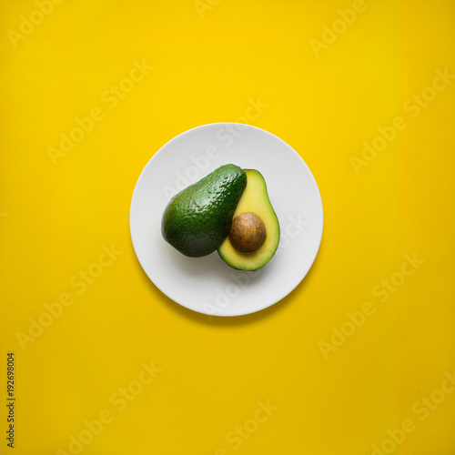 Dinner is served / Creative concept photo of avocado on painted plate on yellow background.