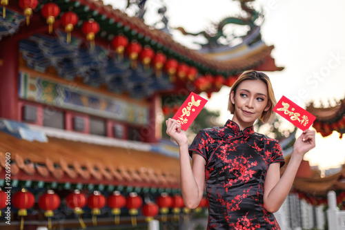 asian lady wearing traditional cheongsam dress with temple and lantern background