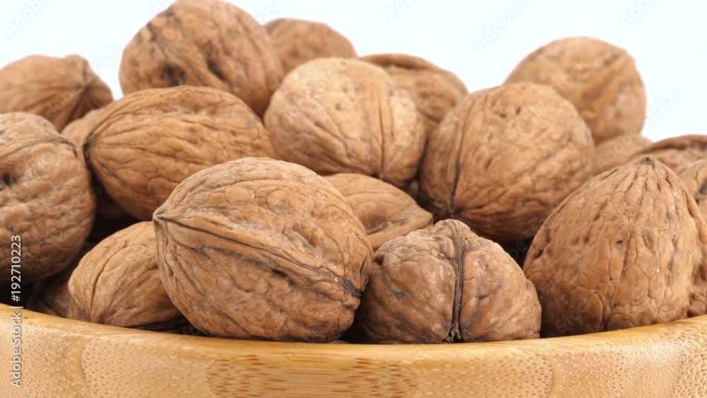Nuts on wooden bowl rotation, white background, closeup