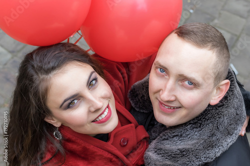 love story. A young man and a young woman with red accessories are walking in the city