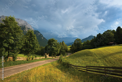 Country road, fence, grass field in Alps, Germany
