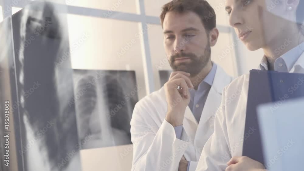 Doctors examining a patient's x-ray and discussing Doctors examining a patient's x-ray and discussing