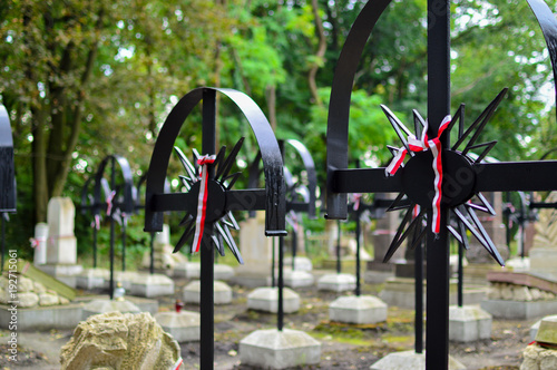 Ribbon with national colours of Poland tied up to the old cross on the cemetery. Rebelion uprising concept. photo