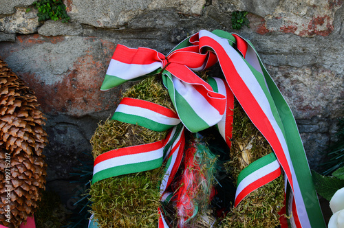 Ribbon with national colours of Hungary tied up to the flower tribute standing near to the old castle wall in Mukachevo, Ukraine. National memory day concept. photo