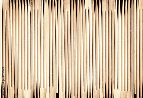 Many Asian wooden chopsticks arranged in a row background. A lot of Chinese traditional eating utensils. Geometrical striped wood pattern photo