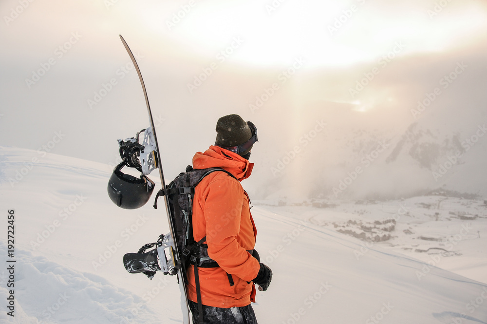 Front view of snowboarder looking on mountain peaks Front view of snowboarder looking on mountain peaks