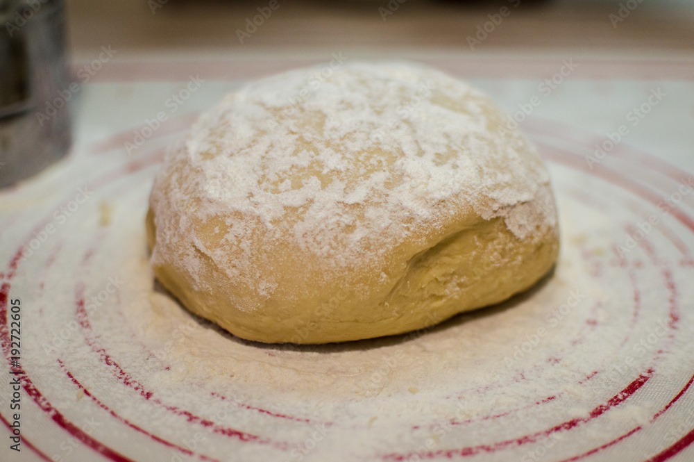 Close-up view of the homemade raw wheat dough ball lying on the modern cooking surface. Dough for pizza, pasta, potstickers. Close-up view of the homemade raw wheat dough ball lying on the modern cooking surface. Dough for pizza, pasta, potstickers.