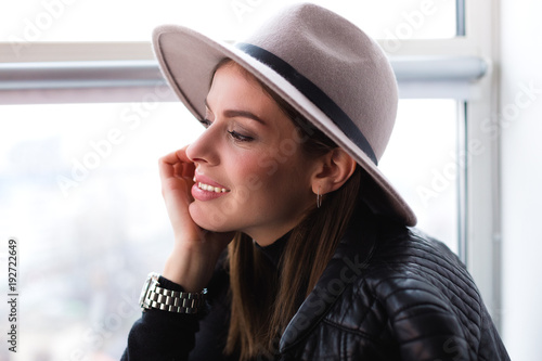 Beautiful boho woman in wool hat sitting by the window