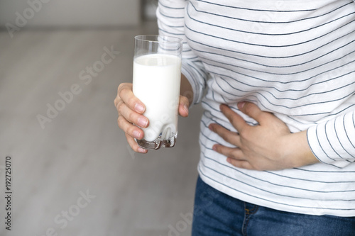 Dairy Intolerant person.Woman with stomach pain holding a glass of milk. Lactose intolerance, health care concept.