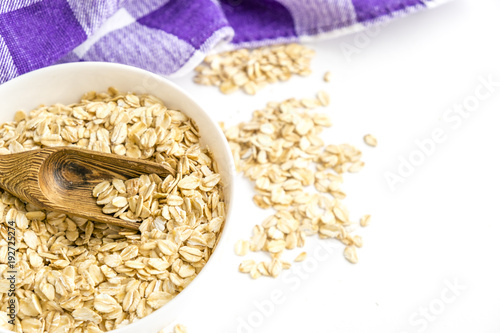 Rolled oats flakes breakfast. Dry oatmeal in bowl isolated on white background. Top view. Delicious Vegan food a hearty cereal photo