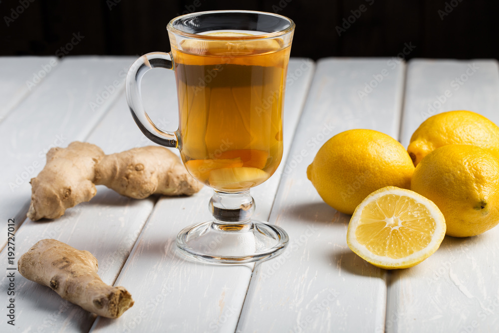 A cup of ginger tea with lemon on a wooden background. A cup of ginger tea with lemon on a wooden background.