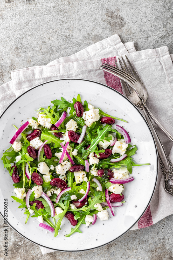 A plate of nutritious simple salad with arugula, beans, soft cheese, onions and oil A plate of nutritious simple salad with arugula, beans, soft cheese, onions and oil