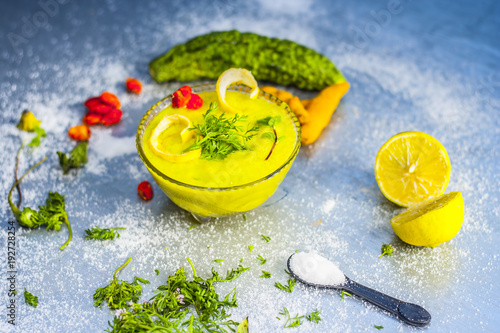 Smoothie made from BITTER GOURD or BITTER MELON with all the ingredients including its seeds on a silver wooden surface.Bitter Gourd Smoothie contains a train of important nutrients ranging from iron. photo