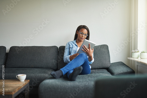 Young African woman sitting at home using a digital tablet