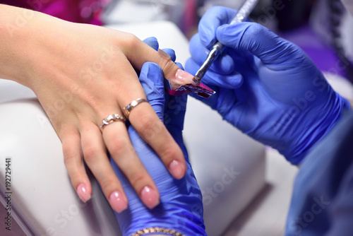 Manicurist with a brush applied to the nails a special gel