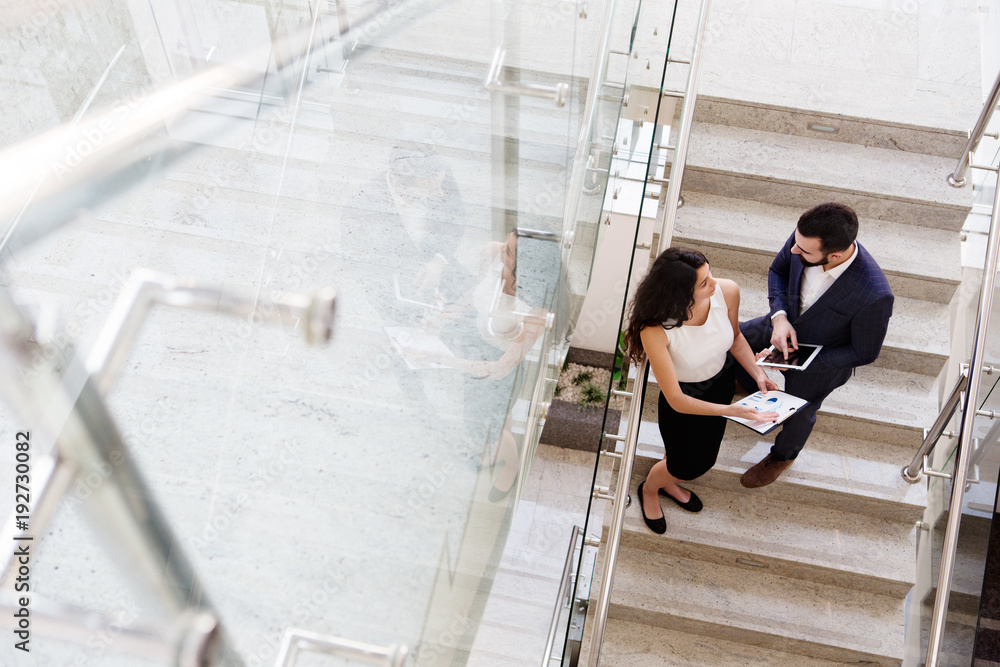 © BigBlueStudio - Two colleagues talk about work outside the office. Top view.
