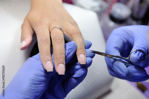 Manicurist with special scissors removes excess skin on the nail  cuticle