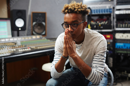 Concentrated guy thinking of working moments or troubles while sitting in studio