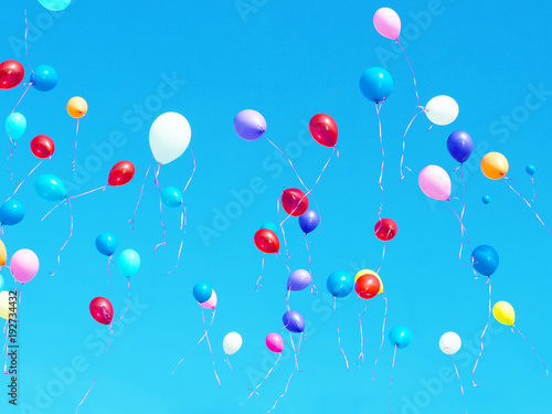 Multicolored balloons filled with helium in the light blue cloudless sky. Flying multicolor balls. Holiday concept