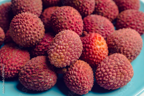 Ripe lychees on the blue plate on white wooden background. Selective focus.