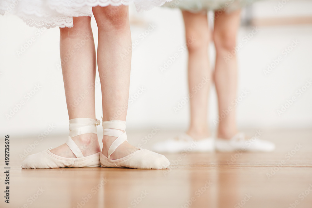 Obraz premium Feet of little ballerina in pointes on the floor during ballet training