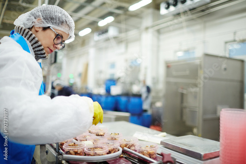 Fotografi Young staff sorting seafood into plastic containers while standing by processing