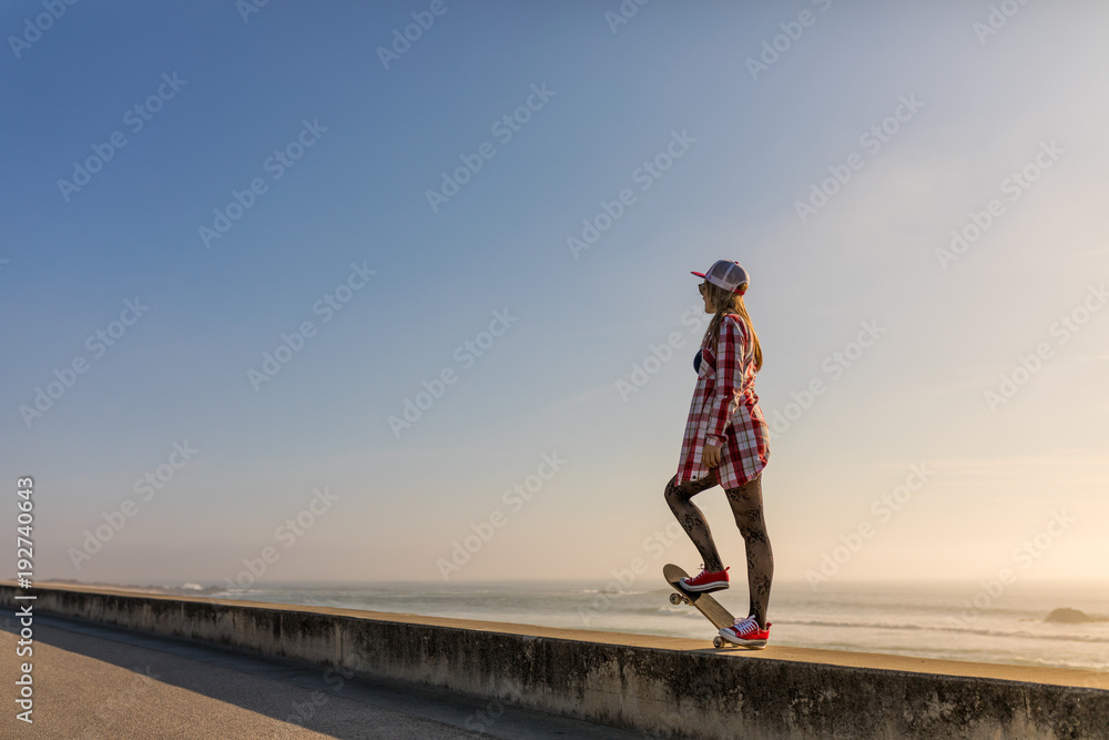 Cute girl with skateboard near the beach at sunset Cute girl with skateboard near the beach at sunset