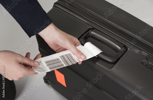 Airline luggage security tag being attached to a travellers black suitcase