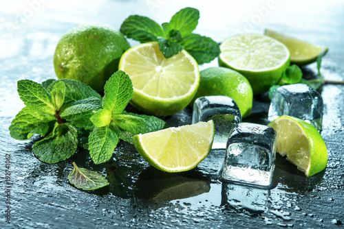 Mint, lime, ice ingredients with water drops on slate