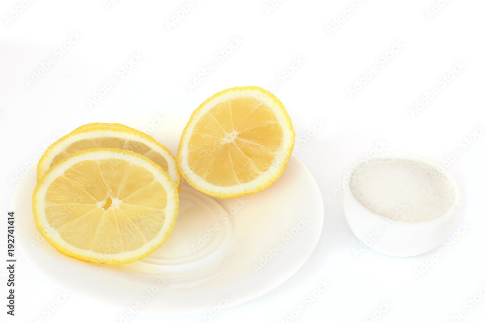 Lemon on a plate and sugar on a white background. Slices of lemon Lemon on a plate and sugar on a white background. Slices of lemon