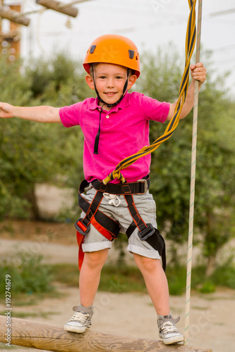 Cute boy enjoying a sunny day in a climbing adventure activity park. Boy at climbing activity in high wire forest park.