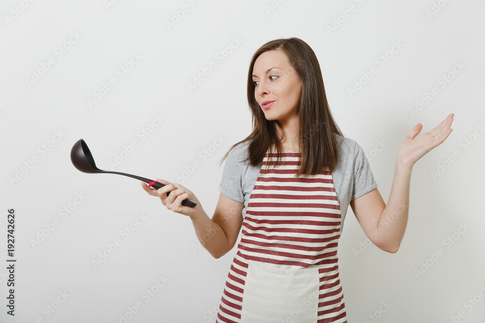 Young attractive smiling caucasian housewife in striped apron isolated on white background. Beautiful housekeeper woman holding black kitchen soup ladle. Copy space for advertisement. Young attractive smiling caucasian housewife in striped apron isolated on white background. Beautiful housekeeper woman holding black kitchen soup ladle. Copy space for advertisement.