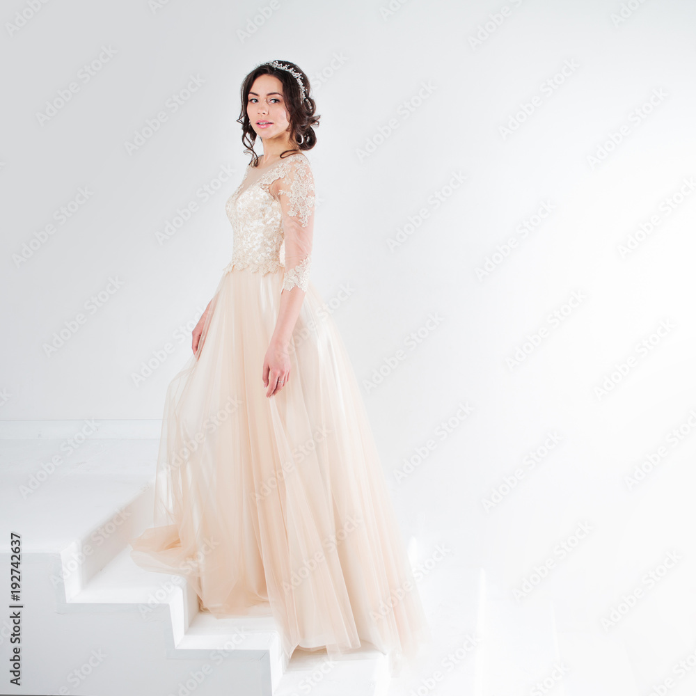 Portrait of a beautiful girl in a wedding dress. Bride in a luxurious dress standing on the stairs, climb up Portrait of a beautiful girl in a wedding dress. Bride in a luxurious dress standing on the stairs, climb up