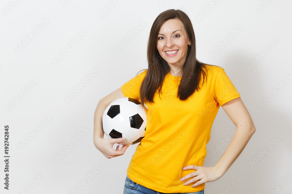 Beautiful European young cheerful happy woman, football fan or player in yellow uniform holding soccer ball isolated on white background. Sport, play football, health, healthy lifestyle concept.
