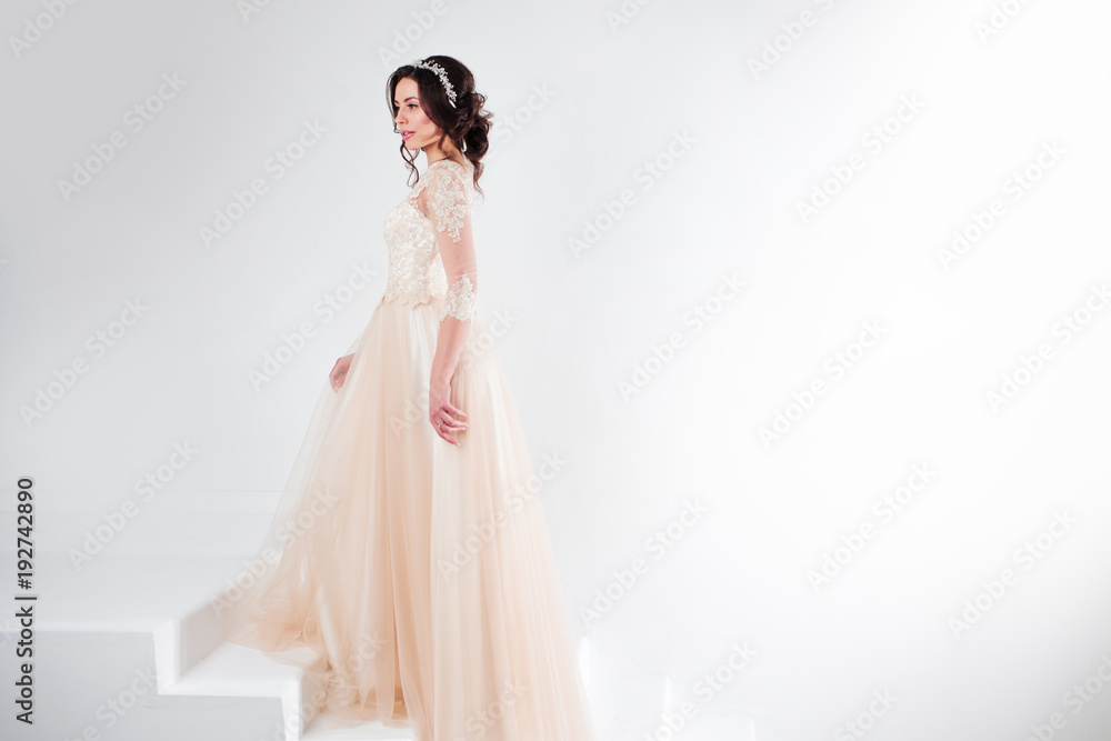 Portrait of a beautiful girl in a wedding dress. Bride in a luxurious dress standing on the stairs, climb up Portrait of a beautiful girl in a wedding dress. Bride in a luxurious dress standing on the stairs, climb up
