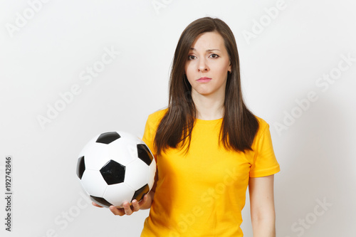 Pretty European young sad upset woman, football fan or player in yellow uniform holds soccer ball, worries about losing team isolated on white background. Sport, play football, lifestyle concept. © ViDi Studio