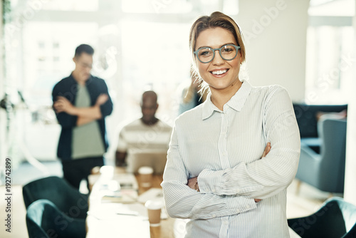 Young businesswoman in an office with coworkers in the background