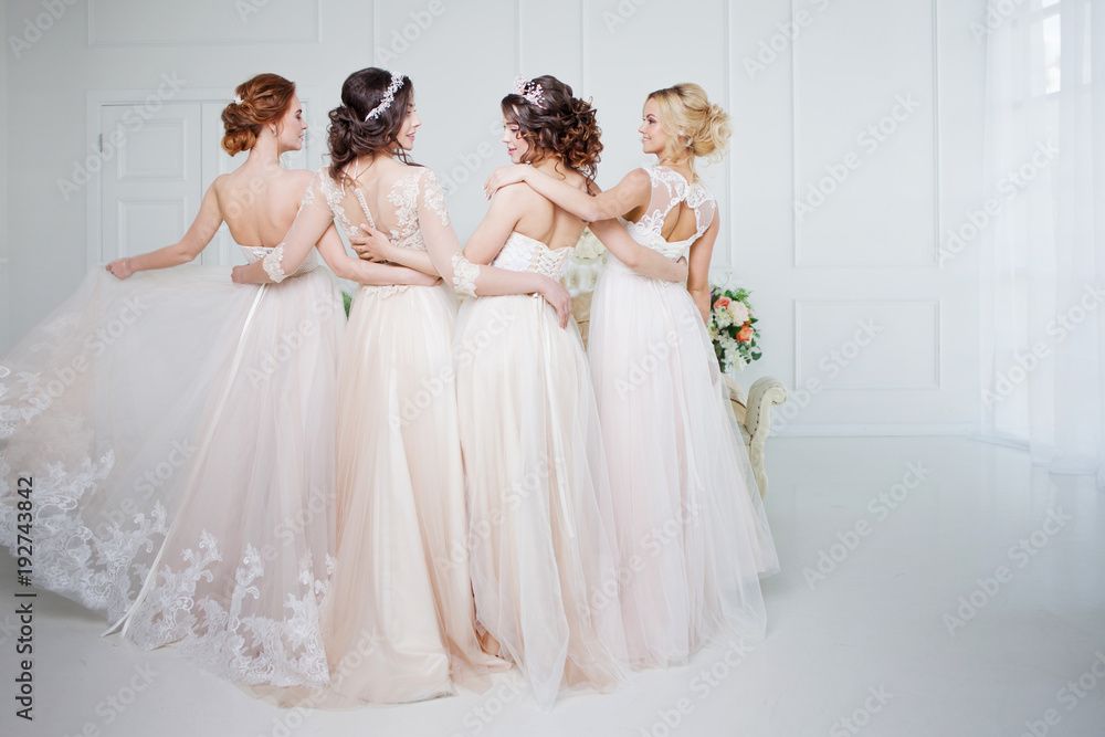 Bride in wedding salon. Four beautiful girl are in each other's arms. Back, close-up lace skirts