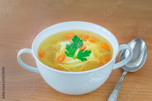 Traditional Polish chicken broth with carrot parsley and spoon.